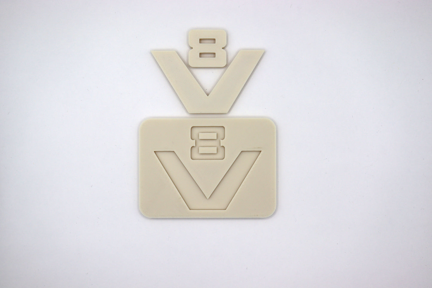 hier zie je een v 8 logo van scania zoals die op de 2 en 3 serie heeft gezeten. met een achterplaatje en het oude v8 logo. het is in een neutrale kleur geprint zodat het naar wens gepoten kan worden. de v en de 8 liggen hier boven het achterplaatje zodat je kan zien dat er in de het achterplaatje een inkeping zit zodat wanner het v8 logo gespoten is het altijd op de juiste plek gelijmd kan worden.